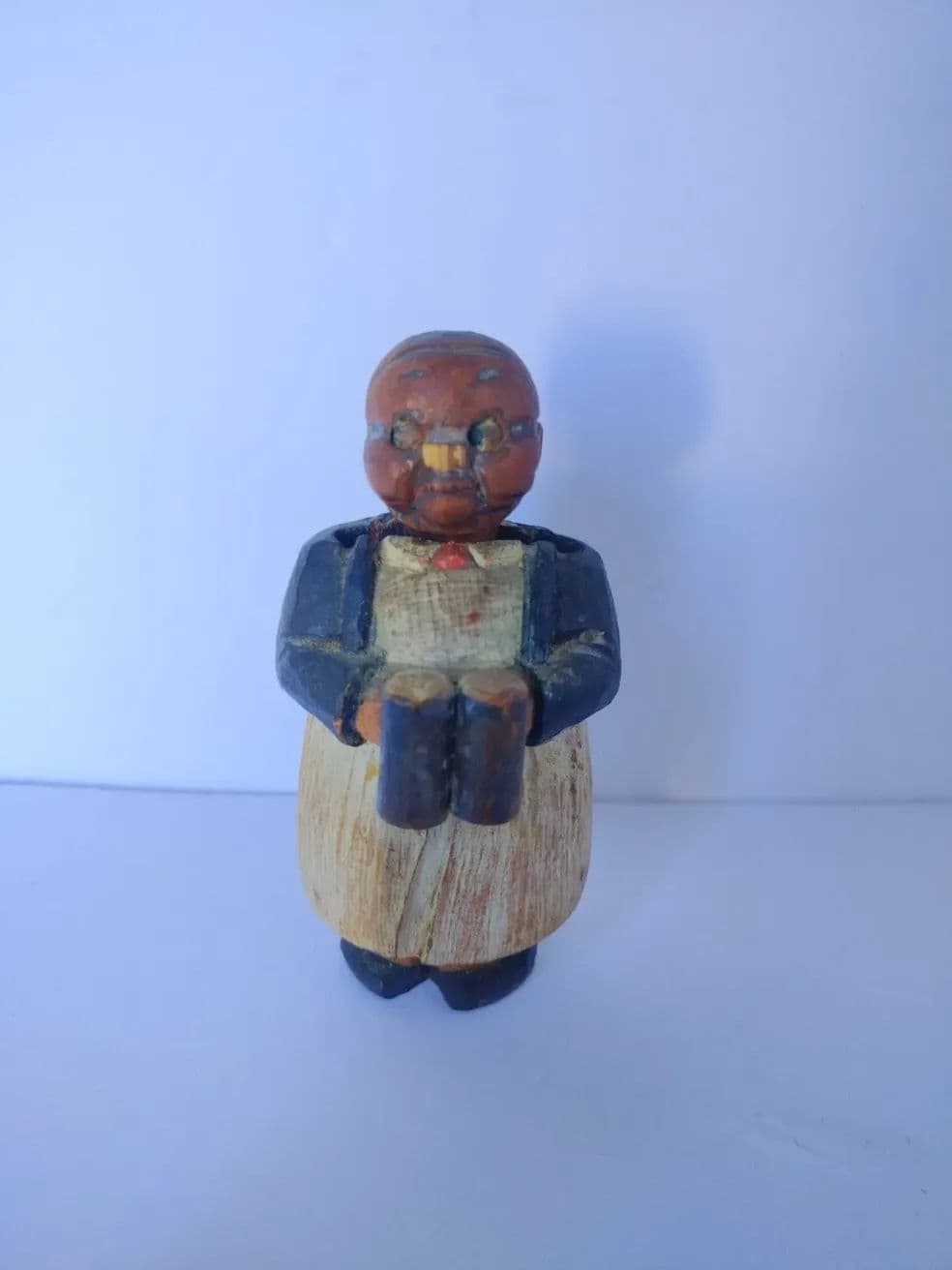 Hand-painted wooden figurine of a person holding a book, dressed in a traditional outfit.
