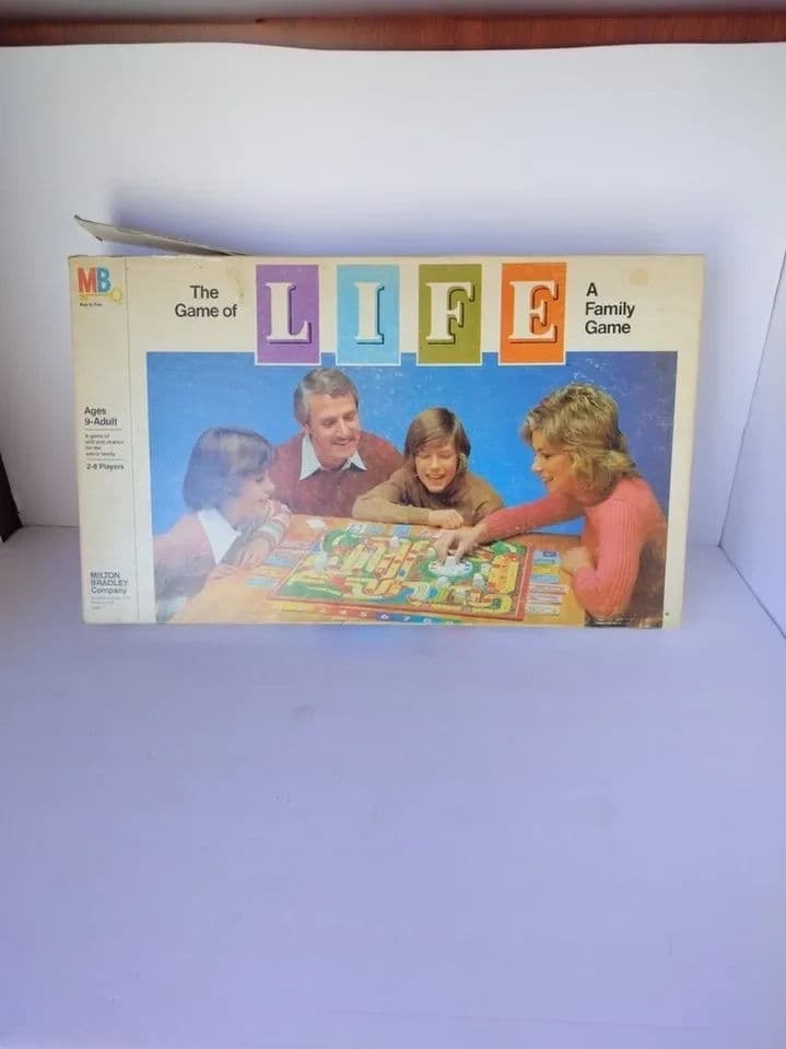Classic board game "The Game of Life" featuring family gameplay scene on the box cover.